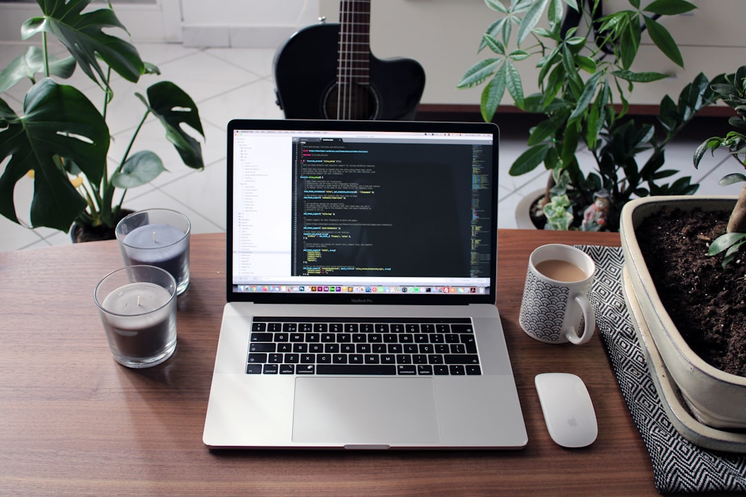 Macbook pro beside white ceramic mug on brown wooden table